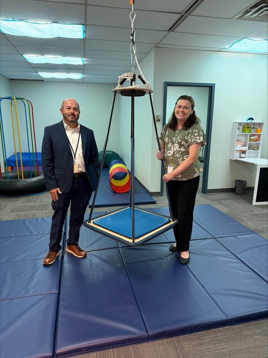 Occupational therapy staff stand near rehabilitation equipment