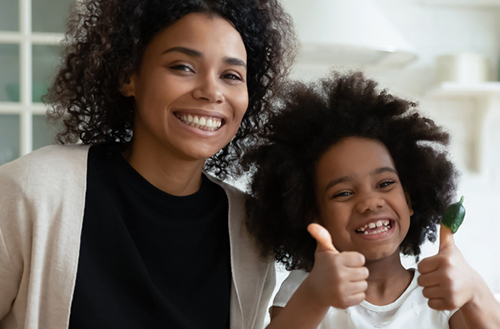 Mother and daughter giving a thumbs up to the camera